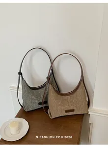 Detailed shot of two woven underarm hobo bags in beige and grey with brown leather straps.