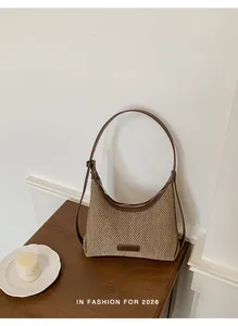 Detailed view of a stylish woven dumpling-style shoulder bag on a rustic wooden table.