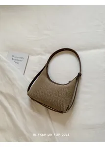 Woven hobo underarm bag with brown leather trim on white fabric background