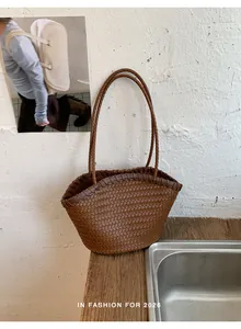 Detalle de bolso cubo trenzado marrón con parte superior arqueada en madera