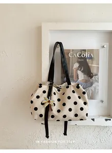 Close-up of a stylish beige tote bag with black polka dots and a palm tree keychain