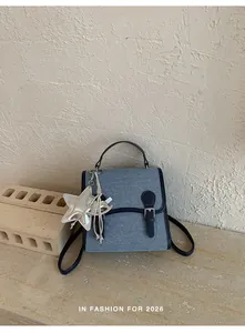 Elegante mochila de mezclilla azul con colgante de estrella plateada en fondo texturizado