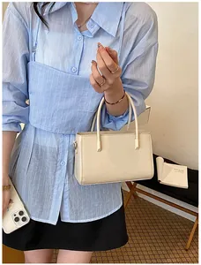 Elegant beige minimalist handbag held by a model in a stylish blue striped shirt outfit