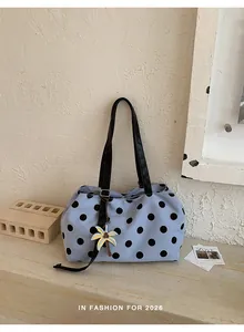 Close-up detail of large blue polka dot tote bag with black straps and palm tree charm