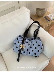 Detailed view of a light blue large capacity tote bag with black polka dots on a white sofa