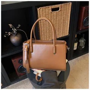 Elegant brown leather tote bag with handle and strap shown in a lifestyle setting