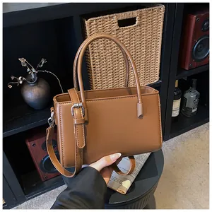 Close-up of a brown leather handbag in a lifestyle setting, showing its sleek handles.