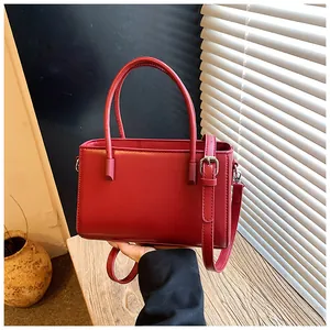 Close-up of a stylish red leather handbag with top handle and adjustable strap