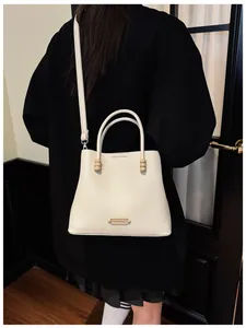 Elegant white pebbled leather bucket bag with wooden beads shown from a back view.