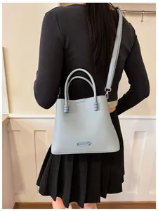 Elegant light blue textured leather bucket bag shown as a crossbody on a female model
