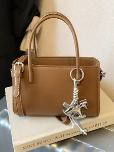 Elegant brown leather handbag with rocking horse charm and adjustable strap