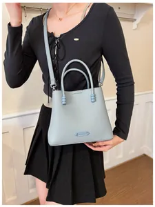 Model carrying a stylish pale blue bucket handbag with leather texture and bead details