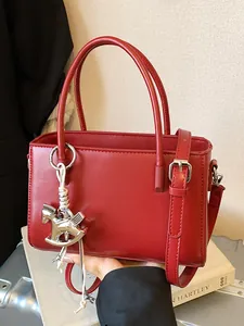 Sophisticated red leather handbag with stylish horse charm for elegant daily commuting