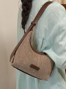 Minimalist beige woven underarm bag with brown leather trim and shoulder strap for women