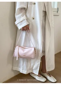 Elegante hellrosa Boston-Tasche, getragen von einem Model im weißen Leinenmantel