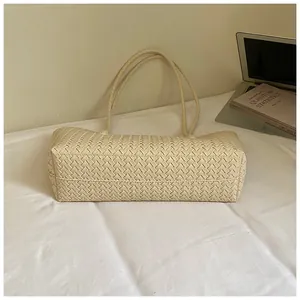Gros plan d'un sac cabas tressé crème montrant la texture et la base rectangulaire.