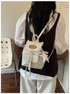 Back view of a white vintage mini backpack with delicate lace trim and star charm