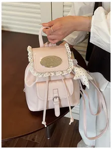 Close-up view of a pink patent leather mini backpack with lace trim and star keychain.