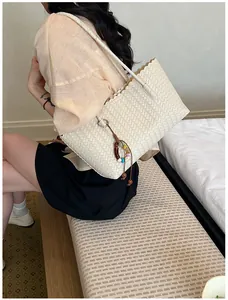 Détail d'un sac cabas tissé avec des bords festonnés et un pendentif coloré