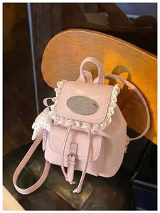 Close-up detail showing the lace trim and metal plaque on a pink mini retro backpack