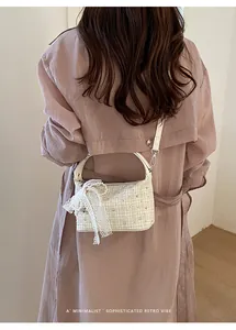 Close-up detail of a beige checkered tweed handbag with lace and pearl charm on a model