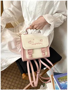 Lifestyle detail of a small pink and cream backpack held by a model in a white dress