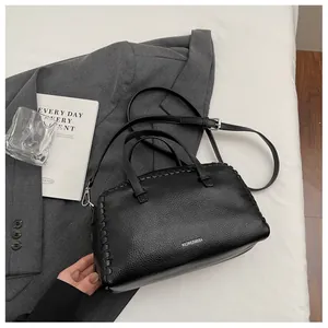 Detail of black lychee texture Boston bag with hand-stitched edges and silver logo