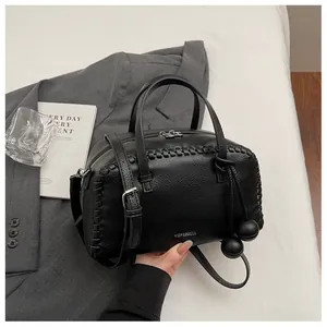 Elegant black leather Boston handbag featuring woven edges and stylish spherical pendants.