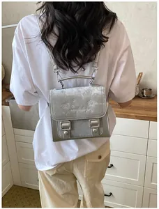 Back view of model wearing a stylish silver embroidered backpack in a kitchen setting