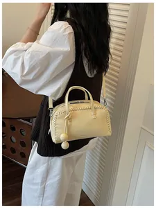 Chic cream-colored Boston handbag with decorative woven edges shown in a lifestyle setting