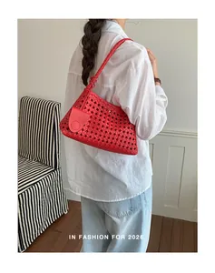 Mannequin portant un sac à bandoulière tressé rouge vif pour un look d'été chic.