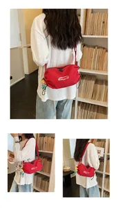 Close-up view of red checkered canvas crossbody bag featuring white BANATU logo and charm