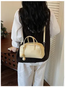 Detailed view of elegant yellow Boston handbag with whipstitch trim worn by model.
