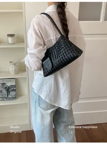 Vue arrière d'un sac à bandoulière tressé noir minimaliste porté avec une chemise en lin.