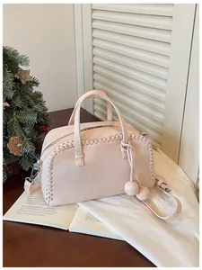 Chic pink pebbled leather Boston bag with woven edges and decorative ball charms.