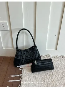 Détail montrant la texture complexe du sac fourre-tout tissé noir et de la petite pochette
