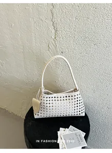 Vue détaillée du sac seau tissé blanc avec breloque cœur sur un tabouret