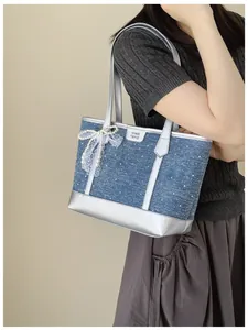 Detailed shot of a stylish blue denim tote bag with silver trim and elegant pearl bow charm