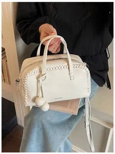 Detail view of cream white Boston handbag with whipstitch trim and ball charms.