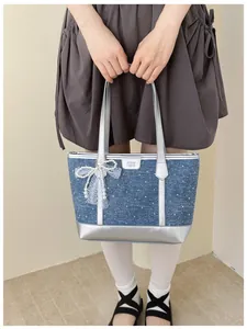 Detail showing blue denim tote bag with elegant pearl bow and silver trim detail