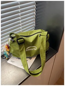 Detailed view of green checkered canvas crossbody bag with wide shoulder strap