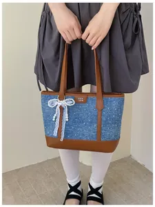 Detailed view of large capacity denim tote bag with brown leather handles and bow charm