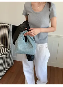 Nahaufnahme einer blauen strukturierten Handtasche, die von einem Model gehalten wird