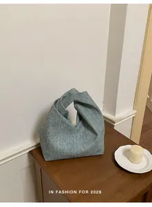 Detailansicht einer hellblauen, strukturierten Wolkentasche auf einem Holzschrank.