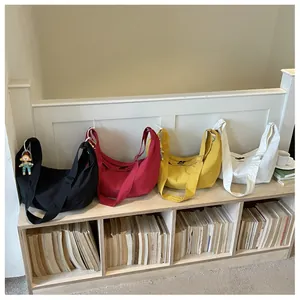 Lichte nylon halvemaantassen in vier kleuren op een houten bankje getoond
