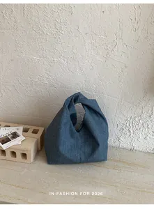 Detailansicht einer marineblauen plissierten Jeans-Croissant-Tasche vor strukturierter Wand