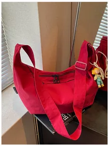 Gedetailleerd overzicht van een rode nylon schoudertas met een cartoon bedel en parelketting