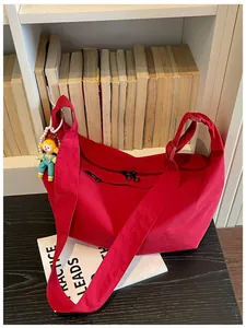 Detailweergave van rode nylon hobo-tas met een schattige poppenhanger voor een boekenkast