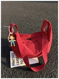Detailweergave van een rode nylon hobo tas met een schattige poppenhanger en parelketting