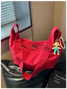 Casual rode nylon crossbodytas met een schattige poppenhanger en parelketting.